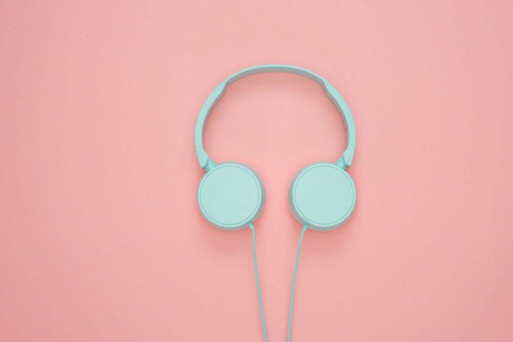 blue over the ear headphones sitting on a pink plain background