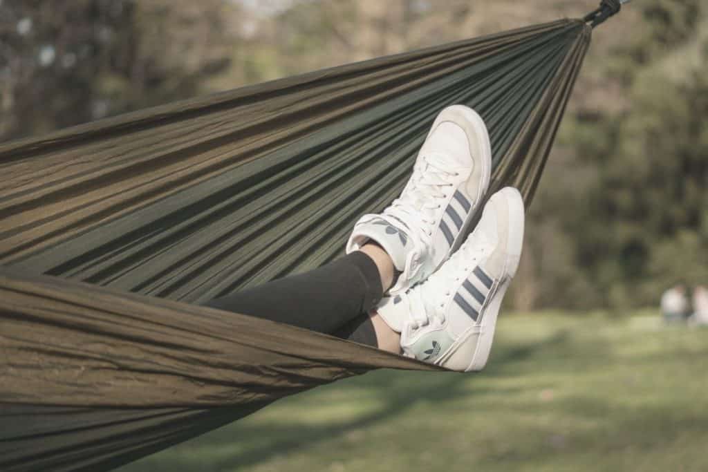 feet in Adidas sneakers poking out the bottom of a camping hammock