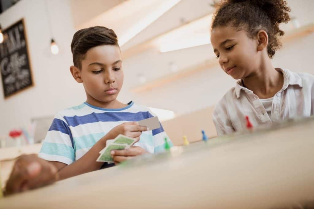 a boy and a girl carefully reading a card as they play a board game