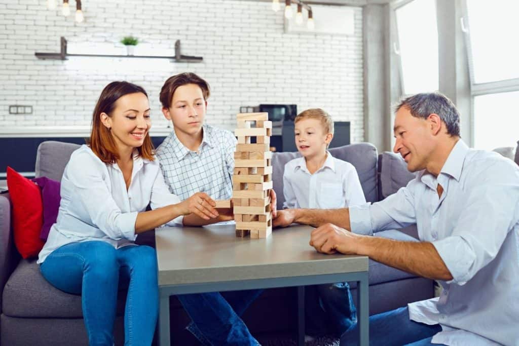 family playing the game Jenga and trying to pull out blocks without tipping the tower