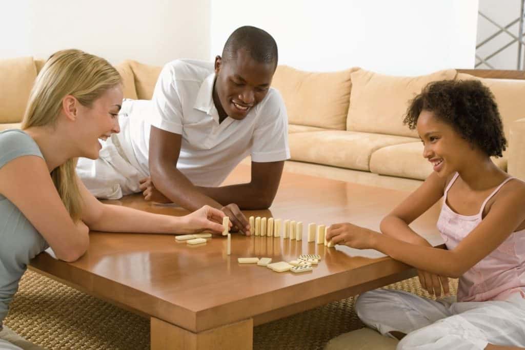 parents and a teenage girl playing a game of dominoes