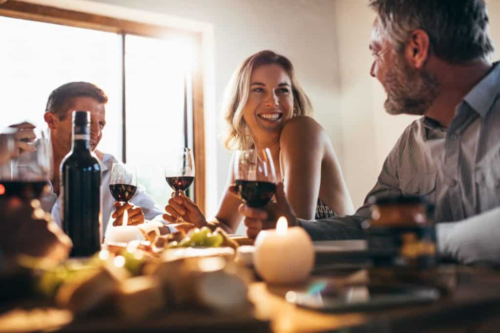 Three people enjoying a meal and wine together. Woman is smiling