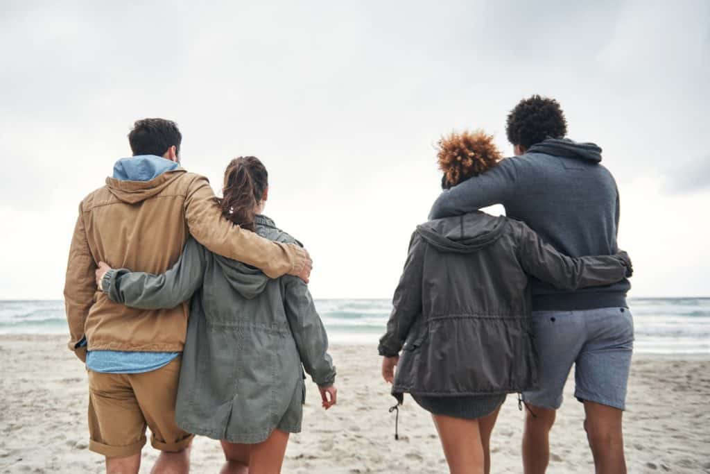 Two couples walking away from the camera on the beach