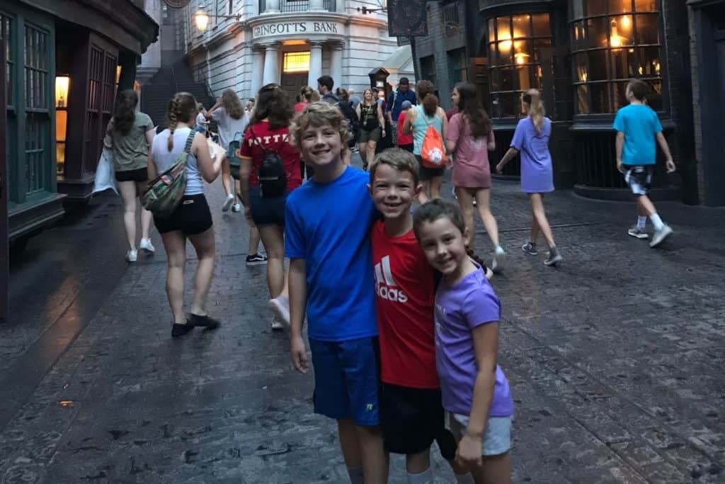 three kids standing in front of Gringott's Bank at the Wizarding World of Harry Potter