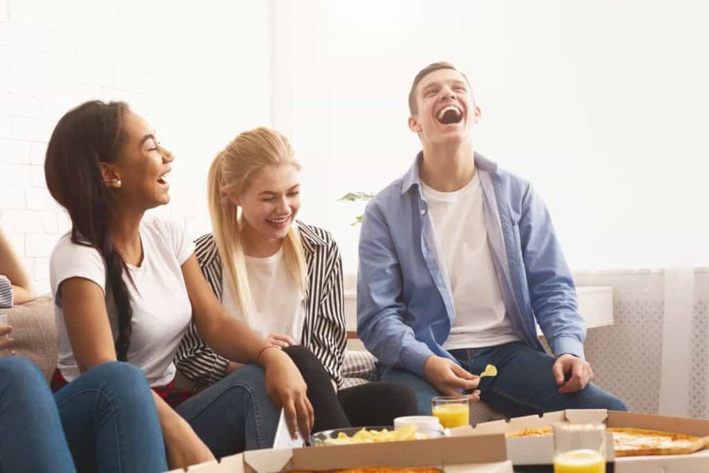 Teenagers laughing and eating as they play a game