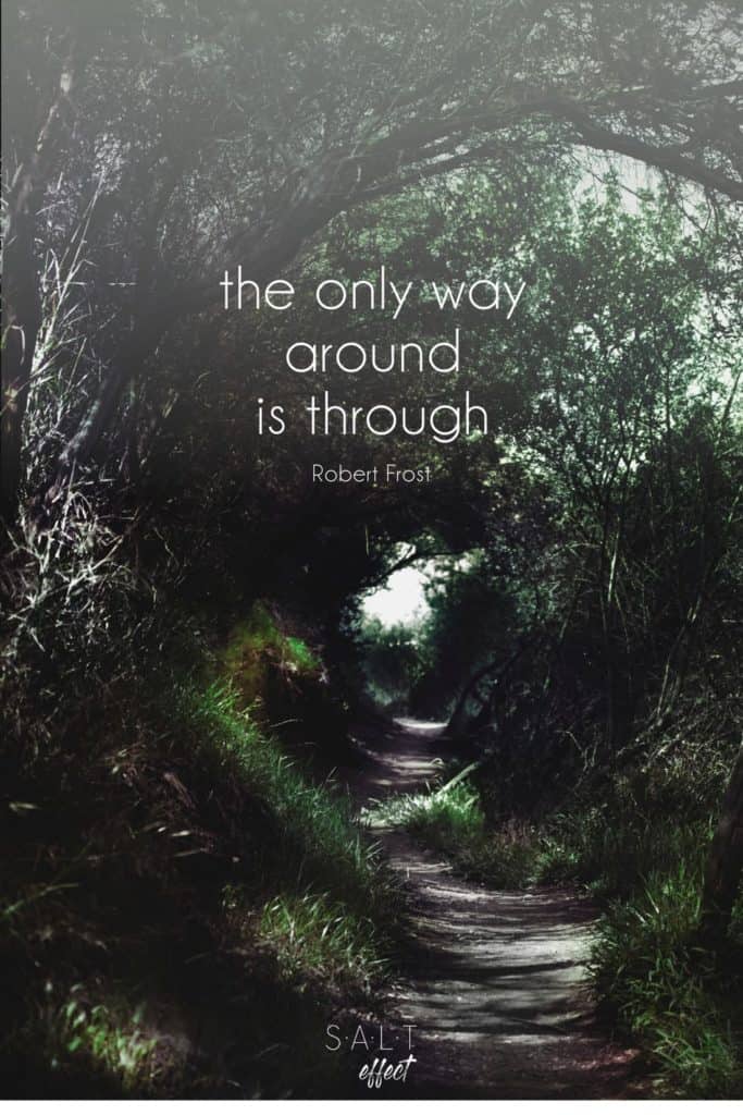 "The only way around is through." Quote by Robert Frost in white text on a background of a path through the woods with green grass and green leaves on the trees.