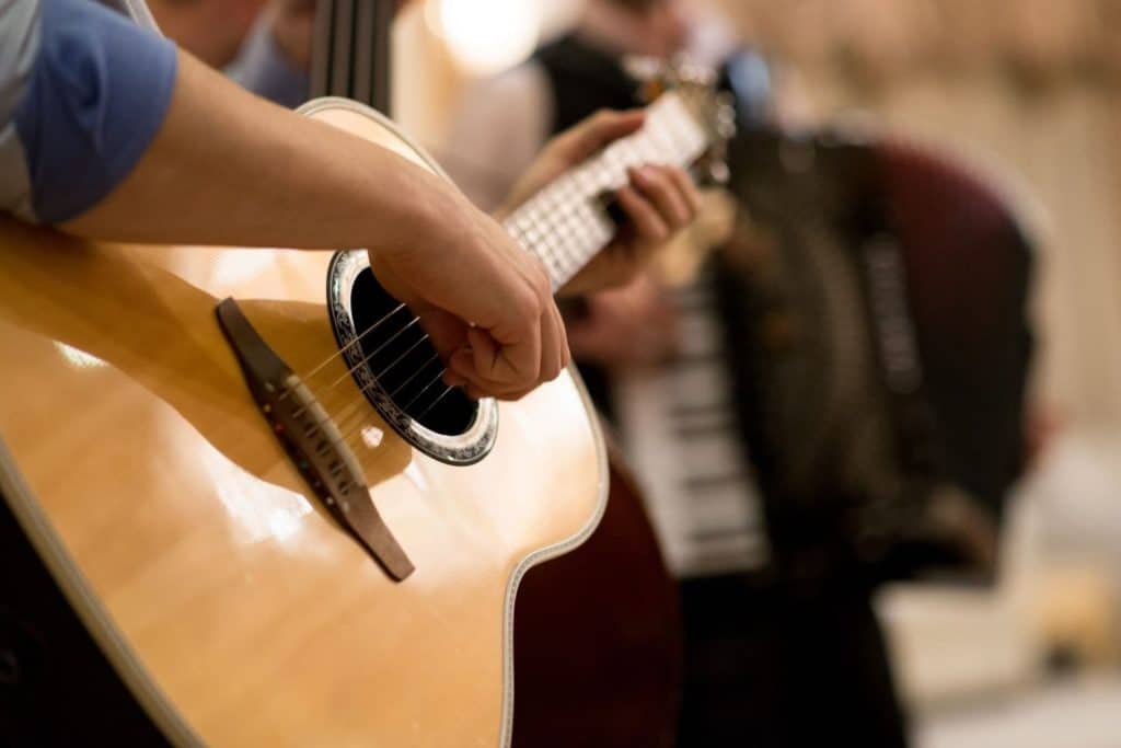 a close-up of a person playing a guitar that only shows the hand and the guitar