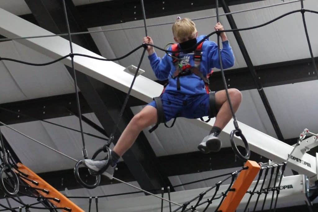 a boy climbing around on an indoor ropes course at PLAY Cbus in Columbus Ohio