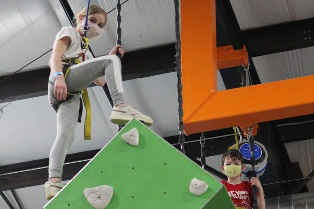 girl and boy at the top of a rock climbing wall at at the indoor climbing course at PLAY Cbus in Columbus Ohio