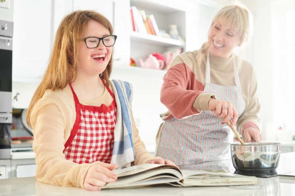 a woman and a girl working together to cook and laughing in the kitchen