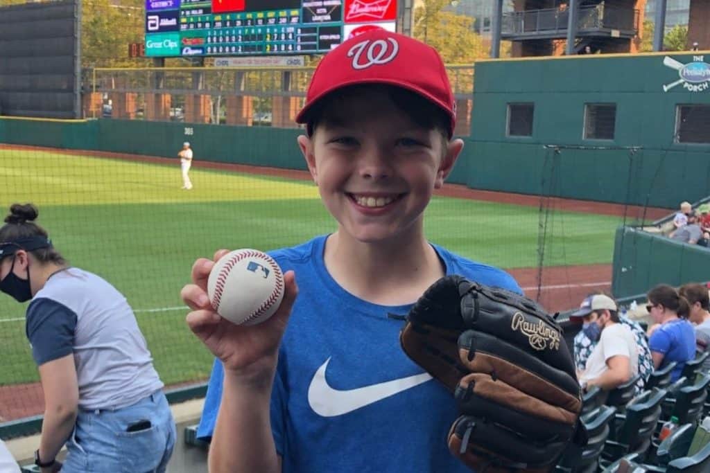 boy holding a glove and ball at a baseball game
