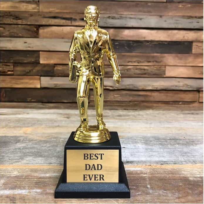 Dundie award, gold trophy of a business person holding a briefcase, engraved with "Best Dad Ever" on the base