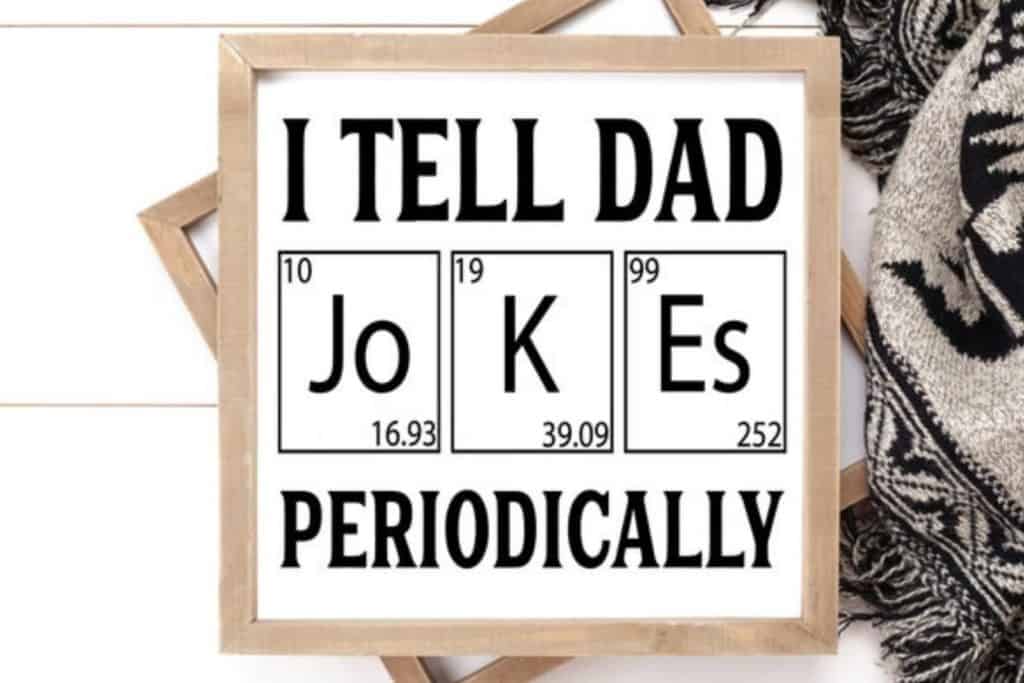 Square sign that says "I tell dad jokes periodically" in black letters on white background and light colored wood border