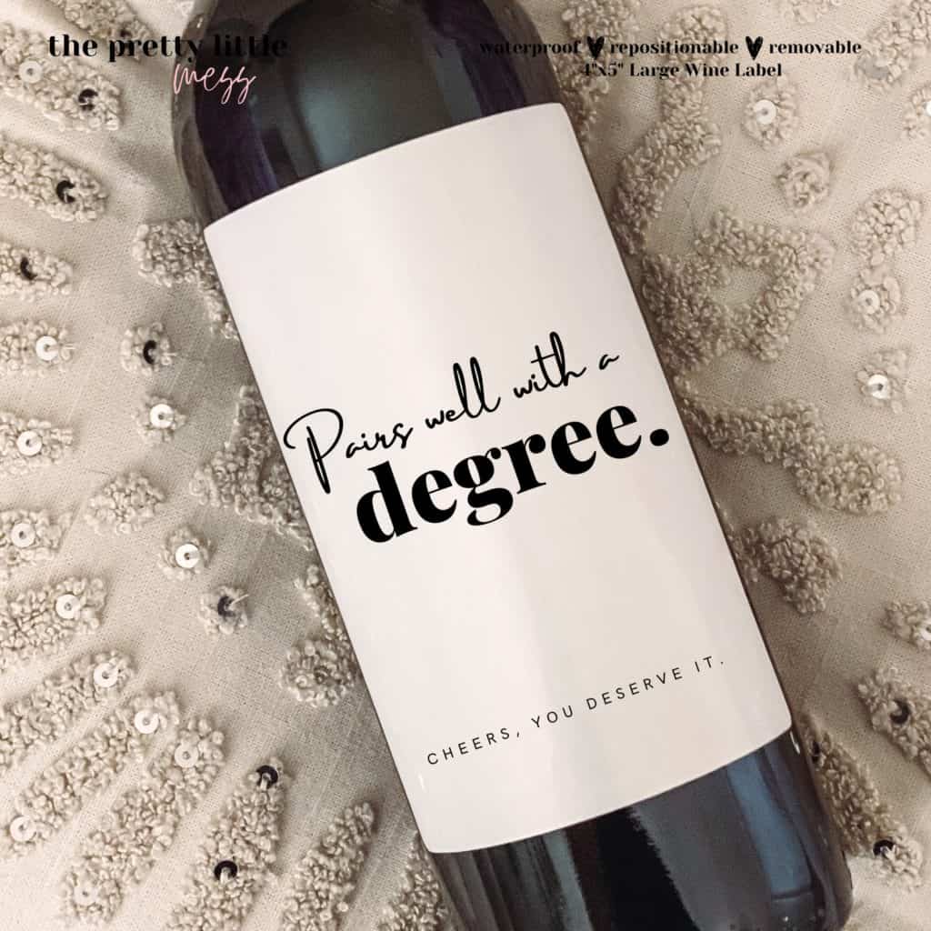 Wine bottle with custom white label for college graduation gift. Says "pairs well with a degree" and "cheers! you deserve it!" in black letters