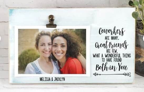 Handmade wood frame painted a soft teal leaning on a counter. Photo of two smiling women under an antique clip on left side of horizontal frame with "Meliss & Jacklyn" below. One right side of frame in black font with arrow below: Cowokers are many. Great friends are few. What a wonderful thing to have found both in you.