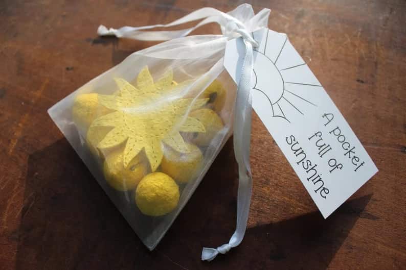 yellow sun seed paper and 10 yellow seed bombs inside a white gauze bag with a tag that says "a pocket full of sunshine"