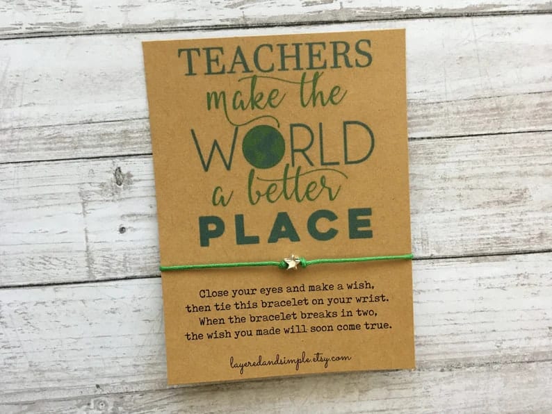 Thin green cord with a small silver star charm wrapped around a craft card that says "teachers make the world a better place"