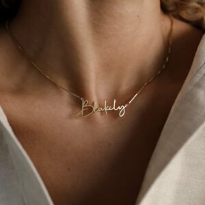 Woman wearing short gold necklace with cursive name: Blakely