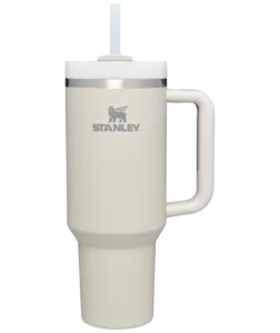 Stanley travel tumbler in matte cream color. White lid with white straw. Stanley name and logo on the front of the bottle.