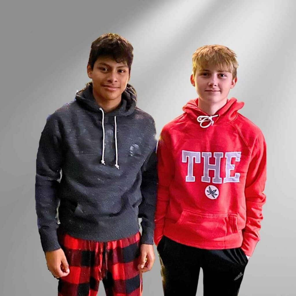 Teenage boys wearing Homage hoodies. One teen with black hair is wearing a heathered black hoodie with script Ohio written in black. The other teen boy on the right is wearing a red hoodie with THE in capital gray letters and a Buckeye leaf.