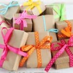 stack of wrapped gifts for teacher moms - brown kraft paper and multicolored bows