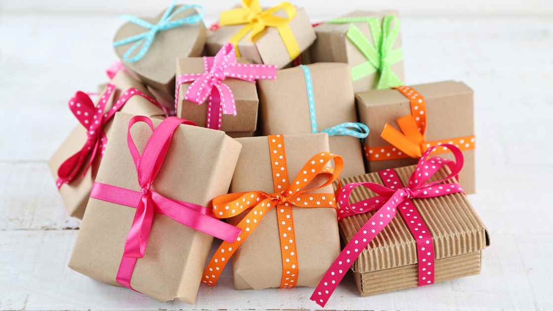 stack of wrapped gifts for teacher moms - brown kraft paper and multicolored bows